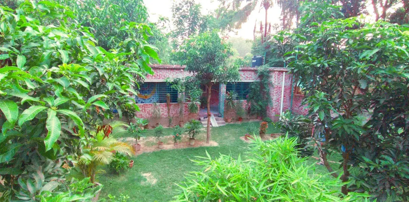 Brick school building in a green garden of mango and banana trees